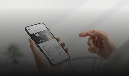 A person holds a smartphone showing an app screen while another hand points at it.