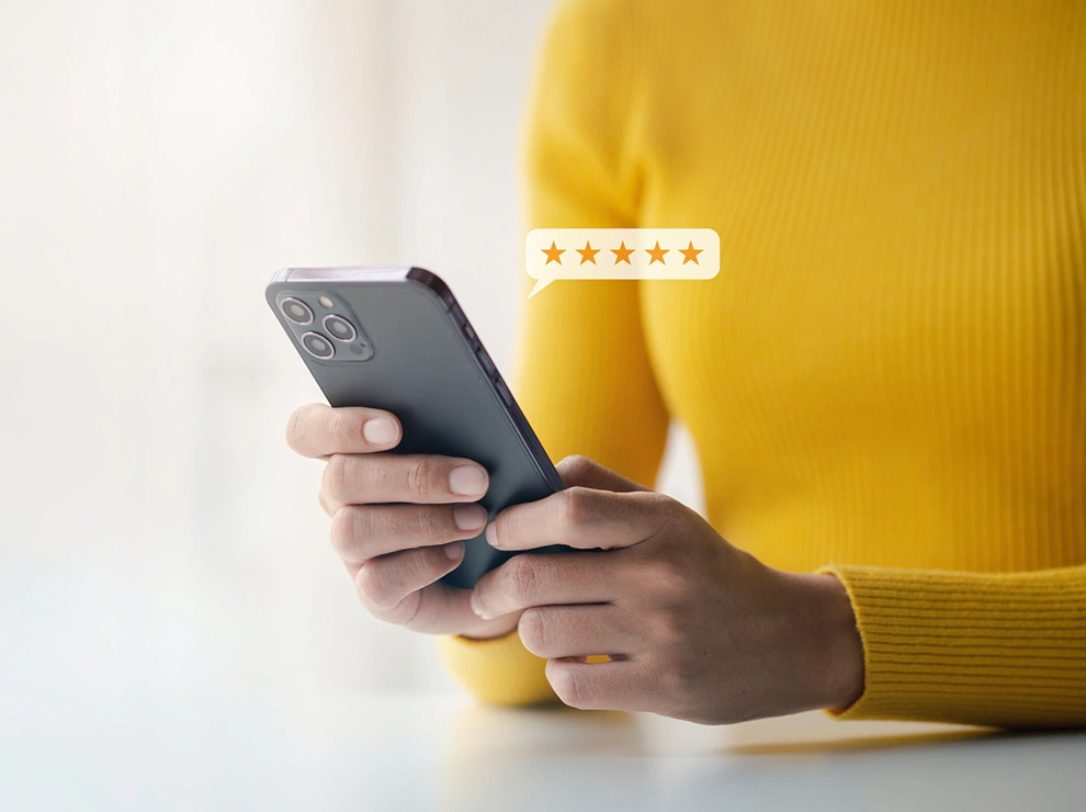 Hands holding a smartphone with a five-star rating bubble floating above the screen.